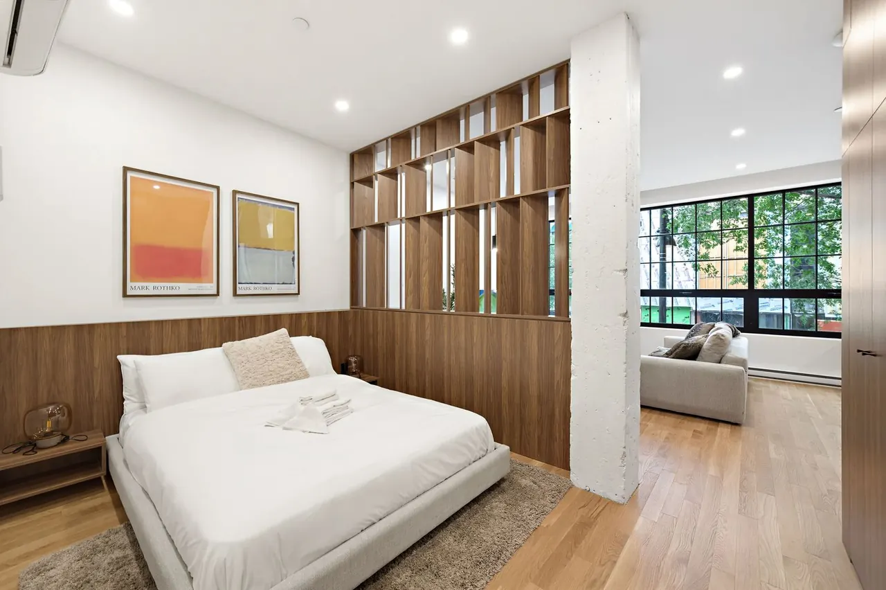 Bedroom with wood-slat divider and view into the living area